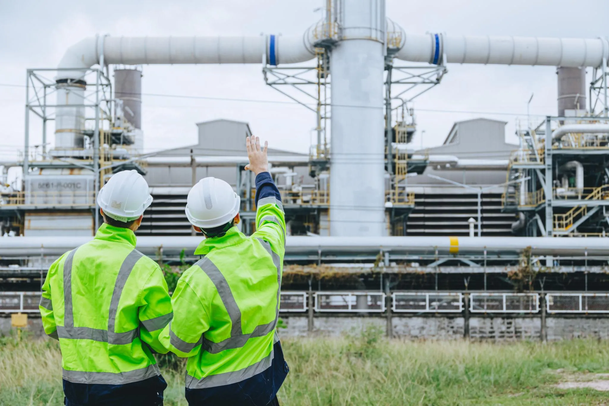 Two Al Yusr Middle East engineers in hi-vis jackets and hard hats inspecting an industrial plant facility in Saudi Arabia