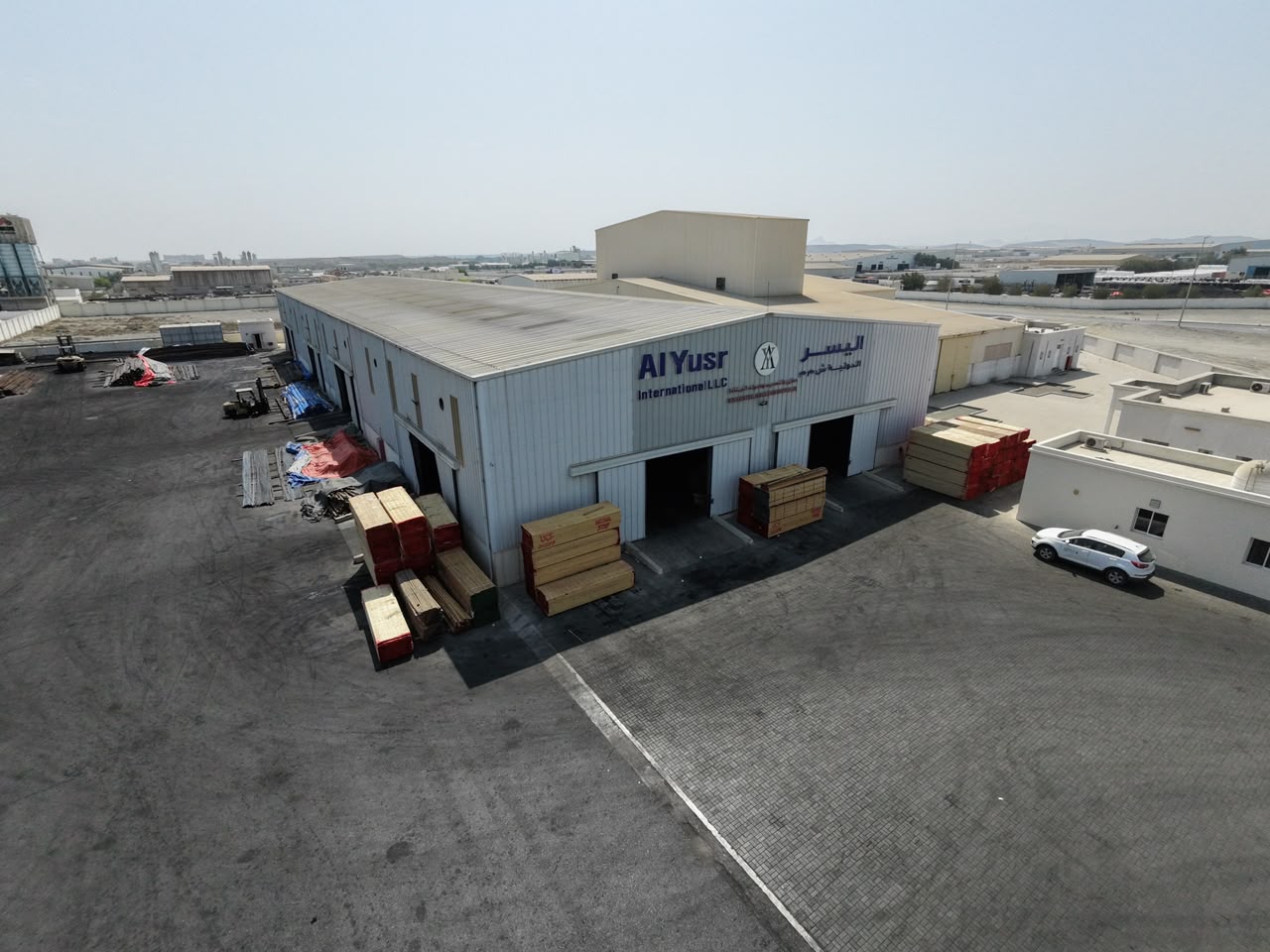 Al Yusr Sohar branch building with timber stacks at the loading bays